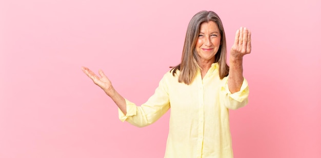 pretty middle age woman making capice or money gesture, telling you to pay