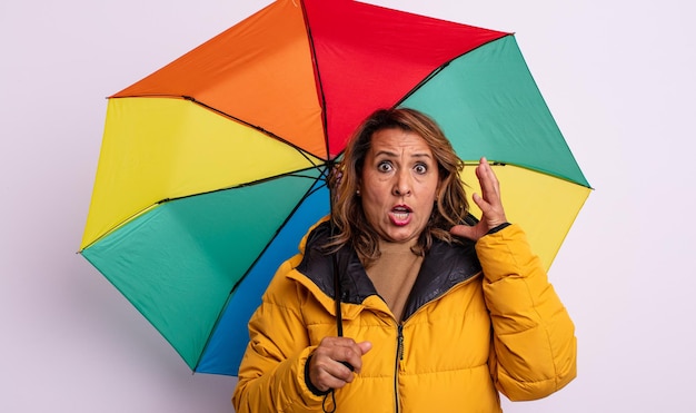 Pretty middle age woman screaming with hands up in the air. umbrella concept