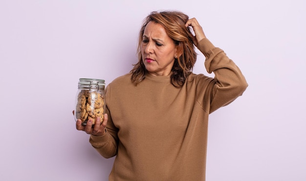 Pretty middle age woman smiling happily and daydreaming or doubting. homemade cookies concept