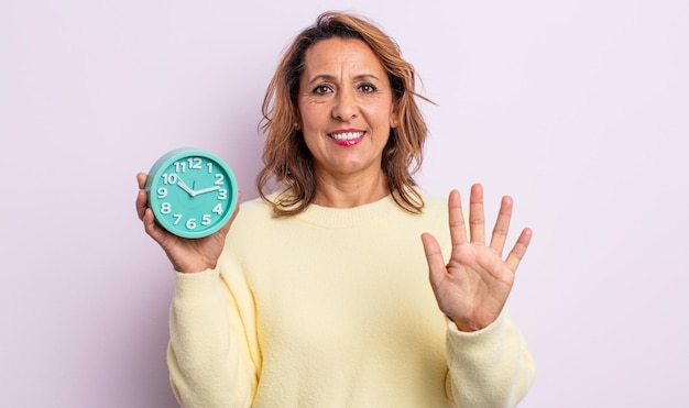 Photo pretty middle age woman smiling and looking friendly, showing number five. alarm clock concept