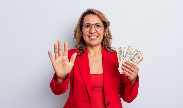 Pretty middle age woman smiling and looking friendly, showing number five. dollar banknotes concept