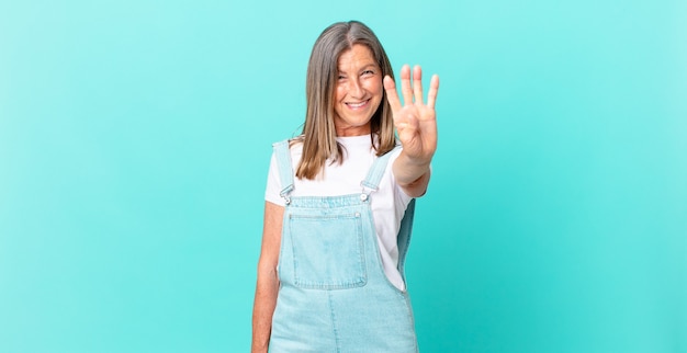 Pretty middle age woman smiling and looking friendly, showing number four