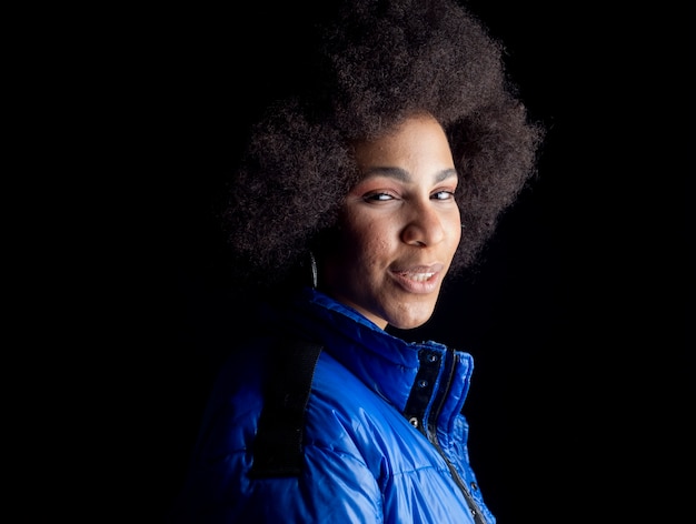 Pretty mixed afro woman, smiling, wearing urban clothes happy smiling on dark surface