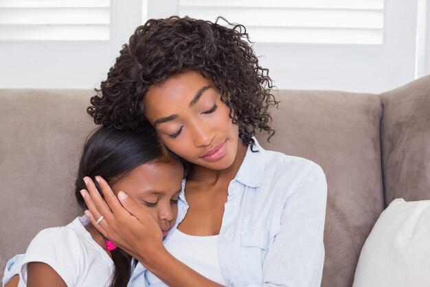 Pretty mother sitting on the couch with her sleeping daughter 