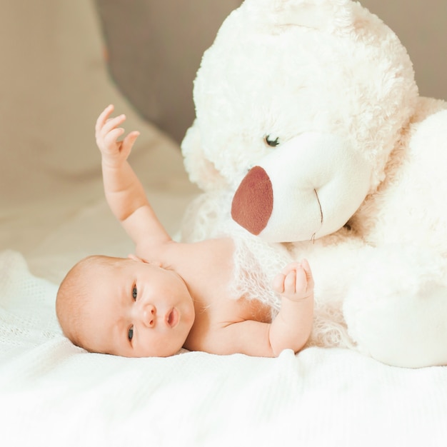 Bella neonata con un grande peluche sdraiato sulla coperta. foto con copia spazio