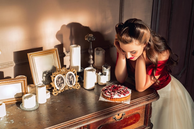 Симпатичная девушка-пинап ест торт в ретро-концепции искушения интерьера