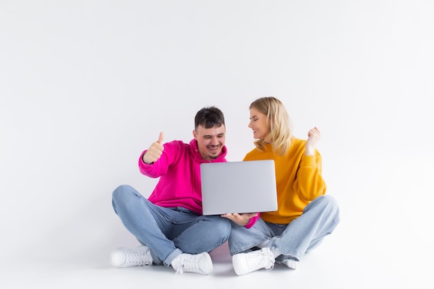 Фото Красивый портрет пары с ноутбуком, сидящей на сером фоне