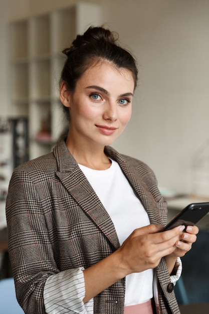 a pretty positive young business woman indoors at home using mobile phone.