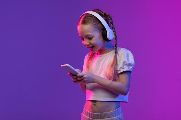 Pretty preteen blonde girl using smartphone and headphones copy space