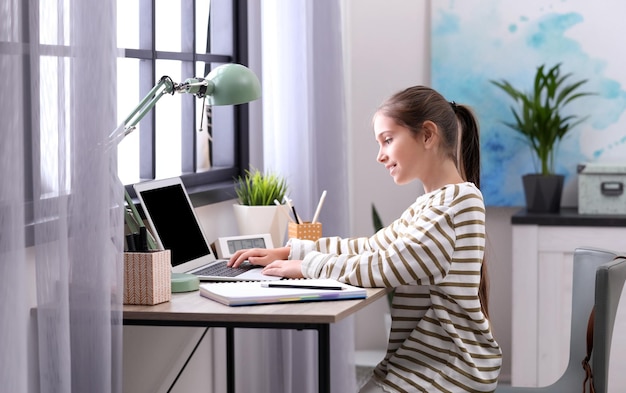 Pretty preteen girl doing homework at table in room