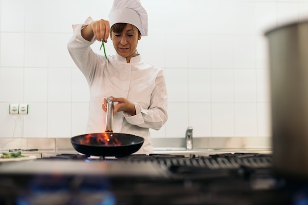 Довольно профессиональный повар готовит на кухне.