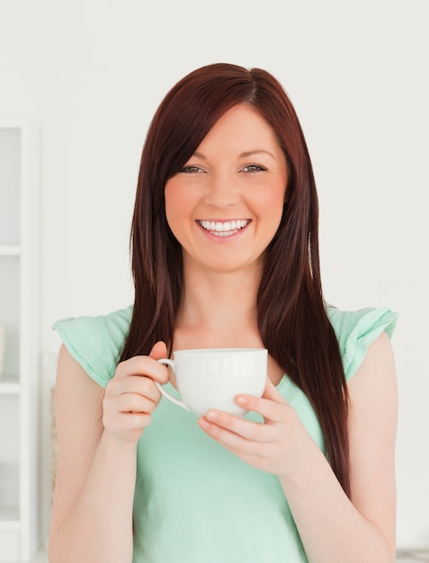 Pretty red-haired woman having her breakfast in the kitchen