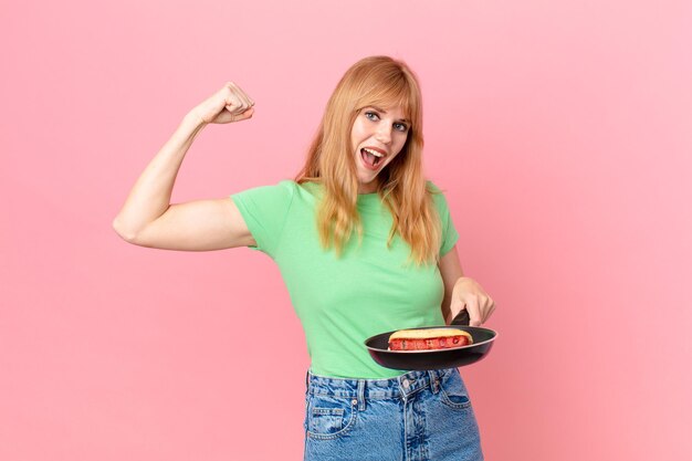 Pretty red head woman cooking a hotdog with a pan