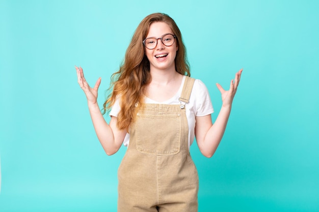 Pretty red head woman feeling happy and astonished at something unbelievable