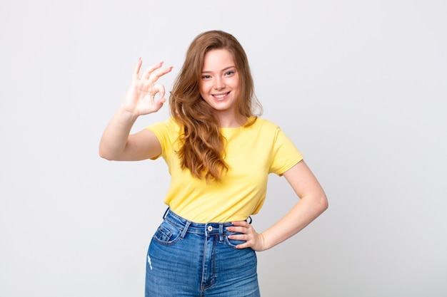 Pretty red head woman feeling happy, showing approval with okay gesture