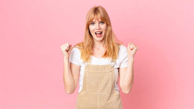 Pretty red head woman feeling shockedlaughing and celebrating success