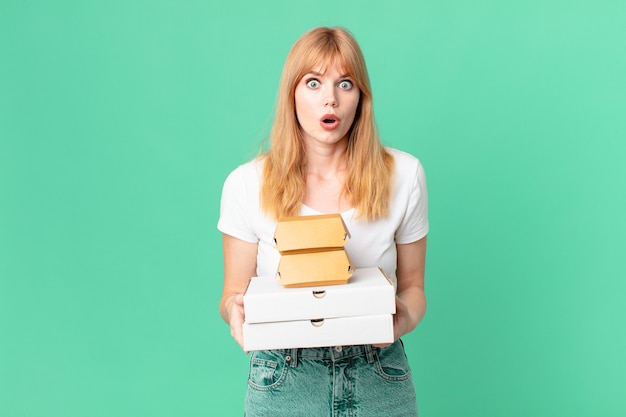 Pretty red head woman holding fast food take away boxes