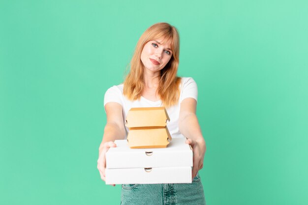 Pretty red head woman holding fast food take away boxes