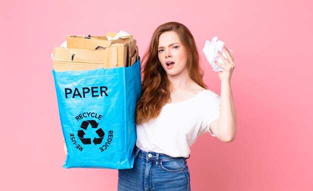 Bella donna dai capelli rossi che tiene in mano un sacchetto di carta riciclata