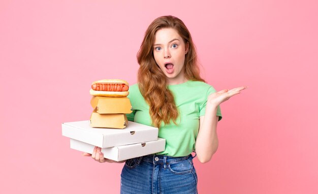 Bella donna dai capelli rossi che tiene in mano scatole di fast food da asporto?