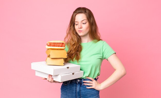 Bella donna dai capelli rossi che tiene in mano scatole di fast food da asporto?