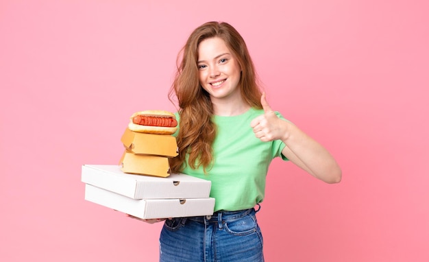 Pretty red head woman holding take away fast food boxes