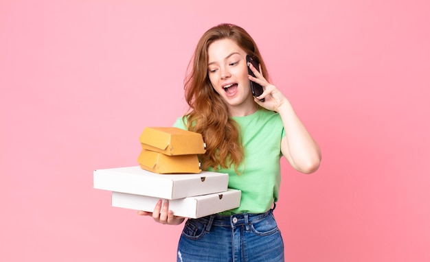 Pretty red head woman holding take away fast food boxes