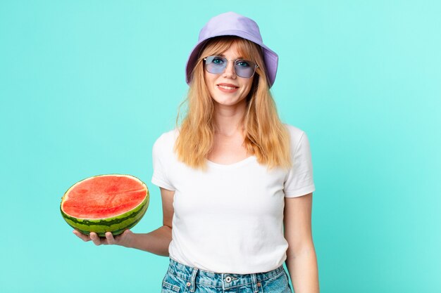 かなり赤い頭の女性とスイカを持っています。夏のコンセプト