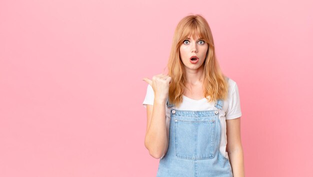 Pretty red head woman looking astonished in disbelief