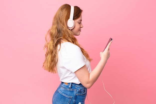 Pretty red head woman on profile view thinking, imagining or daydreaming with headphones and smartphone