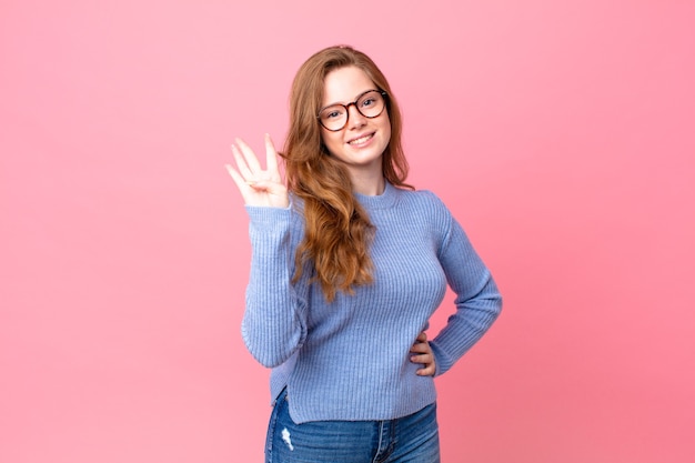 Pretty red head woman smiling and looking friendly, showing number four