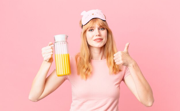 Pretty red head woman wearing pajamas and holding an orange juice. healthy breakfast concept