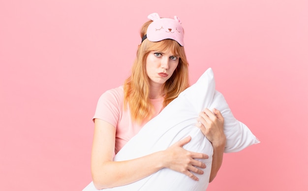 Pretty red head woman wearing pajamas and holding a pillow