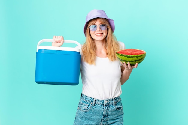 pretty red head woman with a portable refrigerator and a watermelon