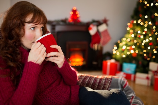 Pretty redhead drinking hot drink at christmas