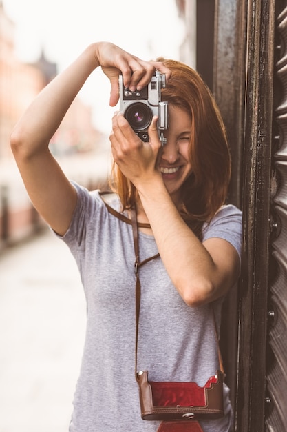 Pretty redhead taking a picture with retro camera