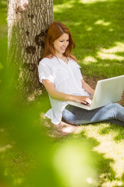 Pretty redhead typing on her laptop 