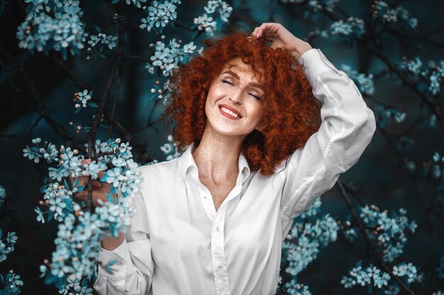 Donna graziosa rossa in un giardino fiorito