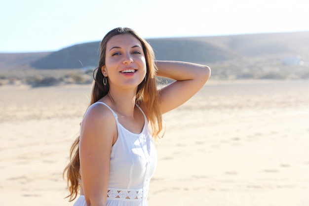 Pretty relaxed young woman smiling, walks on the beach