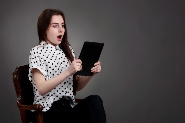 Pretty schoolgirl surprised shocked holding newly launched tablet pc Surfing the net