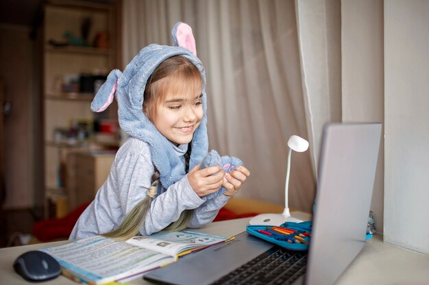 退屈なオンラインレッスン中に耳で面白いウサギの帽子をかぶっているかわいい女子高生