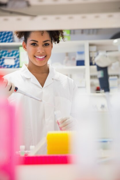 Pretty science student smiling and holding beaker