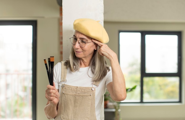 Foto donna piuttosto anziana che sembra sorpresa nel realizzare una nuova idea di pensiero o un concetto di artista pittore