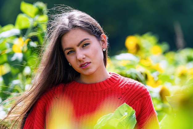赤いセーターを着たひまわり畑でかなり官能的な若いブルネット屋外の幸せな女性