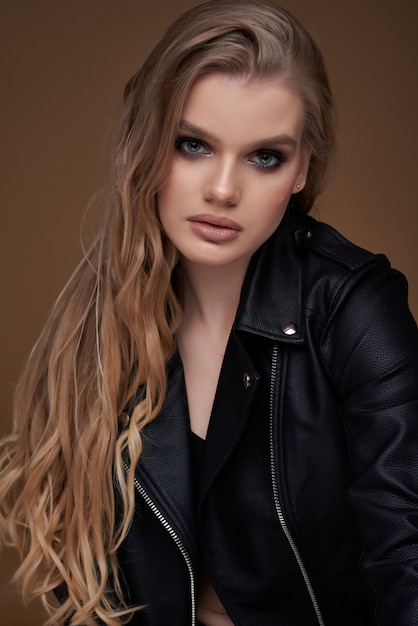 pretty sexy woman posing in studio in black leather jacket and boots