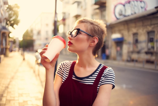 屋外でカップを飲むかなり短い髪の女性