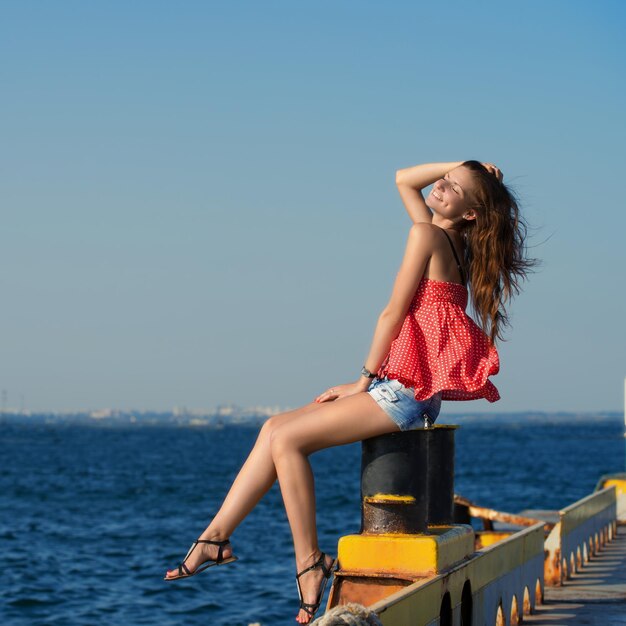 Photo pretty smiling girl sitting at the old berth in summer day