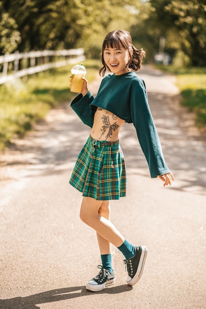 Pretty smiling girl in in a summer park with a glass of lemonade in hand