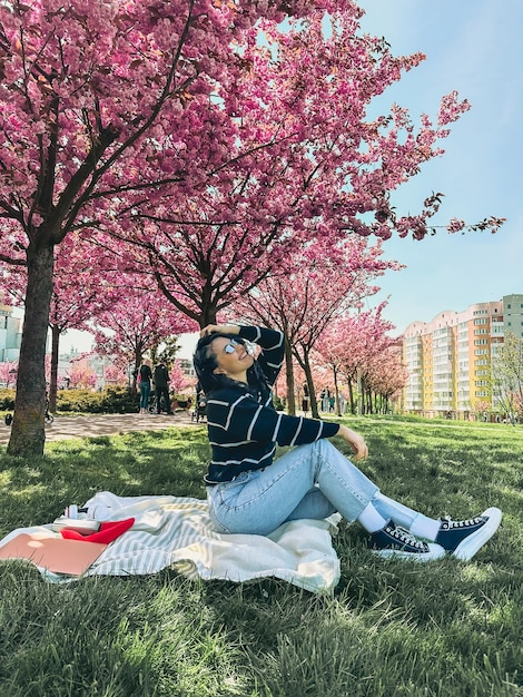 写真 花をかせている桜の木の前でポーズをとっている美しい笑顔の女性