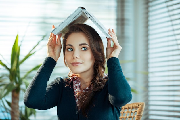 Pretty student holding a book above her head like a roof